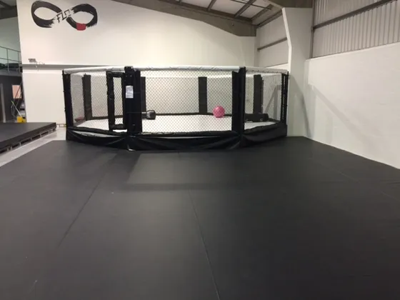 Black floor cover next to cage ring featuring some of our white rope covers and white cage ring floor cover.